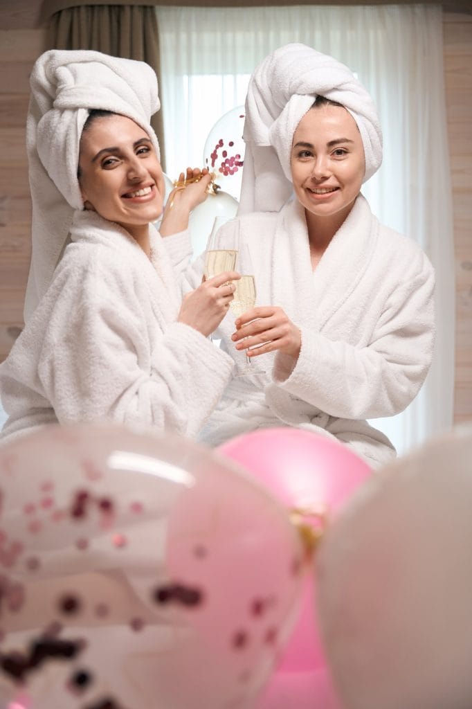 Cheerful young ladies in white bathrobes celebrating bachelorette party